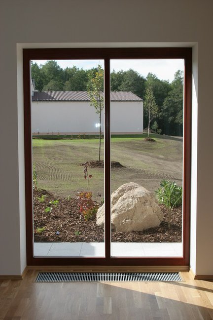 Piękny widok na ogród i wygodne wyjście na taras, dzięki  zastosowaniu grzejnika kanałowego Purmo Aquilo