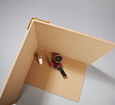 1. Chociaż płyty MDF są ciężkie, ich klejenie jest łatwe i to bez konieczności używania ścisków. Najpierw łączymy ze sobą jedną ściankę boczną i ściankę tylną – powierzchnie stykowe smarujemy klejem (wąskie krawędzie płyty) i łączymy obydwa elementy. Aby obie płyty zostały połączone dokładnie pod kątem prostym względem siebie, należy wykorzystać osobną płytę- -wzornik, której przycięcie najlepiej zlecić w markecie budowlanym. Aby ścianki fotela pozostały na swoim miejscu, gdy klej będzie wiązał, na narożniki naklejamy od zewnętrznej strony po 3 paski taśmy do klejenia paczek.